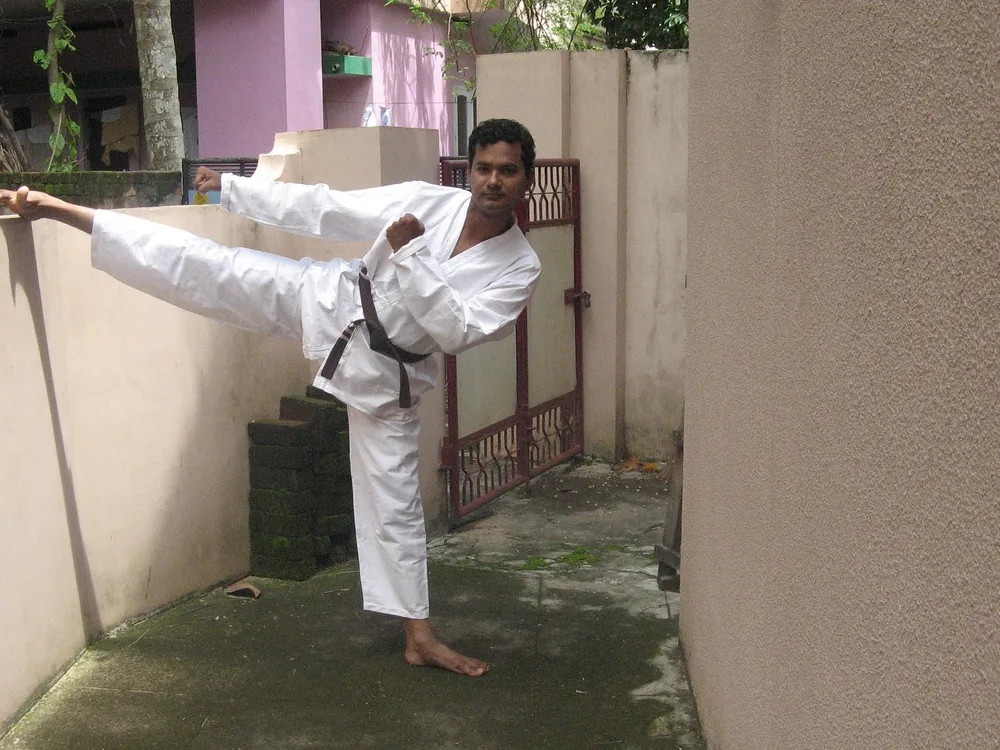 A karateka in a white gi delivering a high kick during training