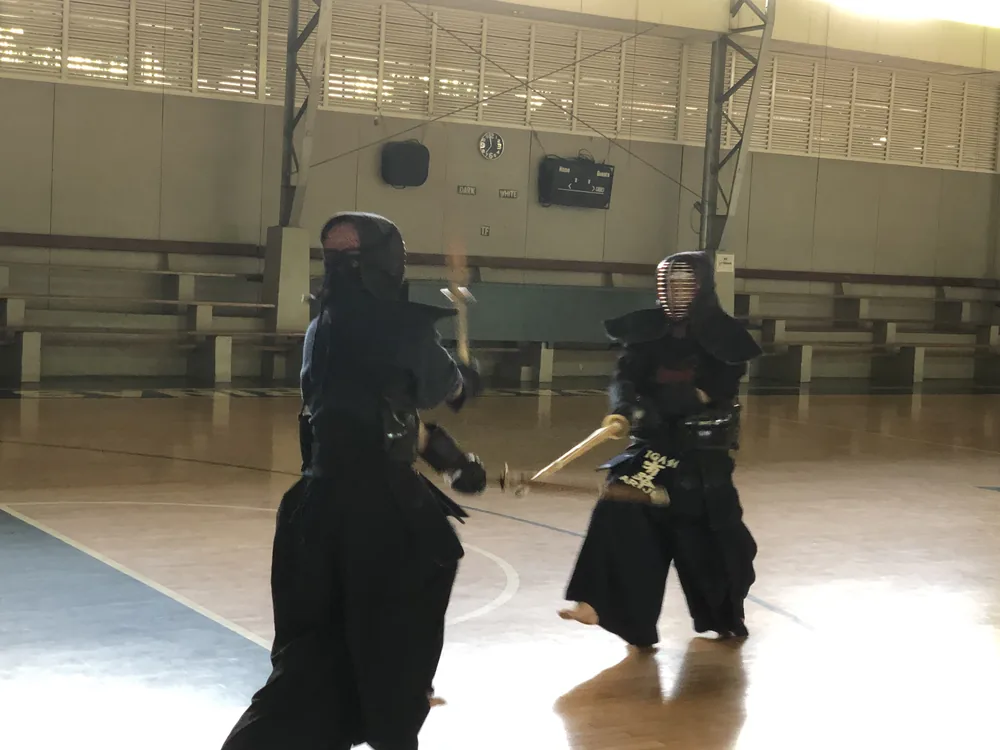 Two kendo practitioners in bogu armor crossing shinai during practice